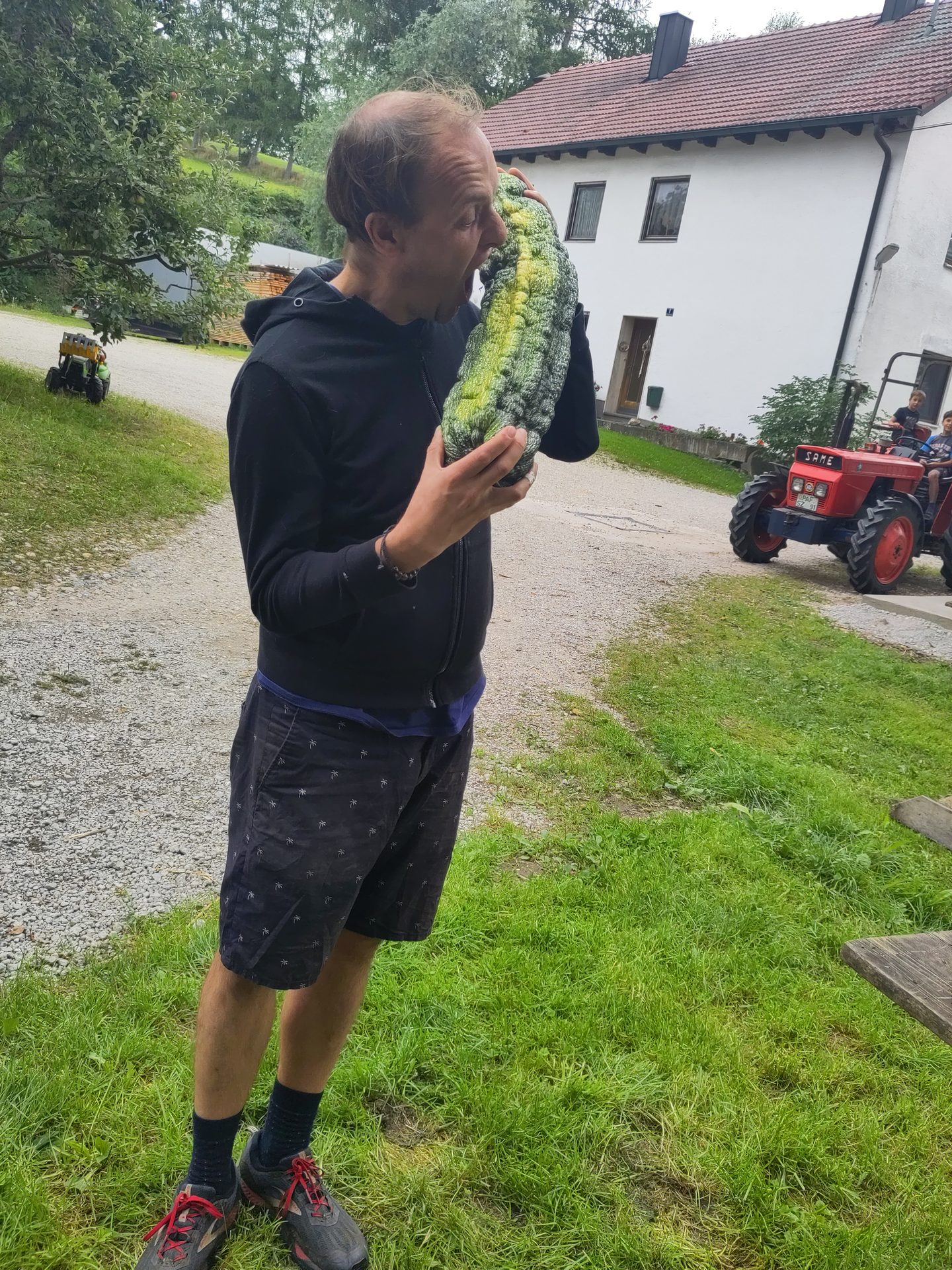 Ein Bimeshof-Mitglied trägt eine riesige Zucchini vom Feld – Erntezeit am Hof